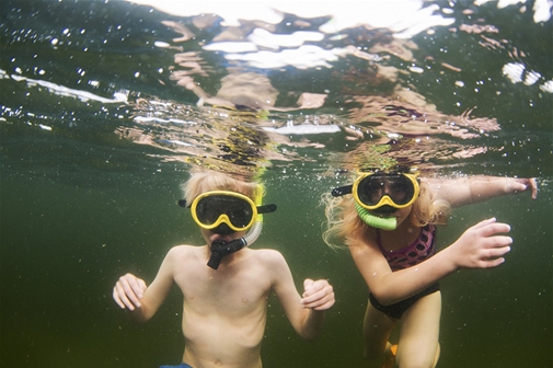 En pojke och en flicka snorklar i vattnet.