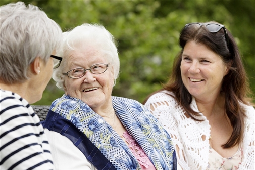 Två äldre damer och en yngre sitter ute tillsammans.