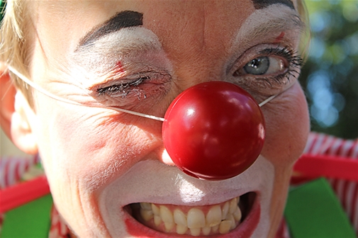 En clown med röd näsa flörtar till fotografen.