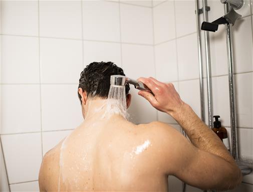 Bilden visar en man som duschar, att undvika att bada är ett bra tips för att spara vatten
